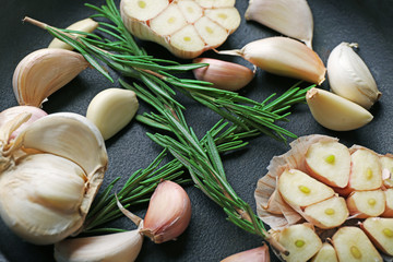 Fresh garlic with rosemary in black pan, close up