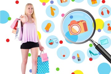 Composite image of pretty young blonde holding shopping bags