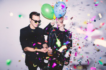 New Year's Party. Girl and boy posing in front of white wall with balloons
 - obrazy, fototapety, plakaty