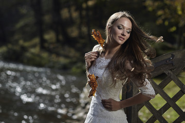 Girl model bride posing outdoors with leaves in their hands.