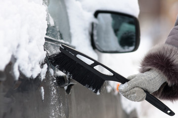 hand cleaning a car from the snow with a brush, closeup