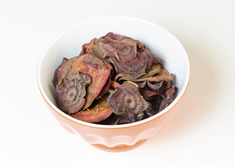 Thin round beetroot chips baked in the oven with oregano and salt and ripe beet roots in a bowl isolated on white background.Healthy,vegetarian,vegan,crispy snack appetiser for diet and clean eating 