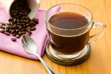 The cup of hot coffee and coffee bean on wooden background