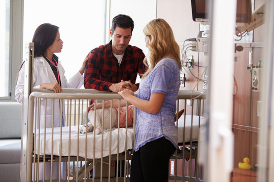 Pediatrician Visiting Parents And Child In Hospital Bed