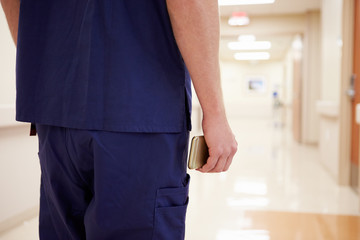 Fototapeta na wymiar Close Up Of Nurse With Cellphone In Hospital Corridor