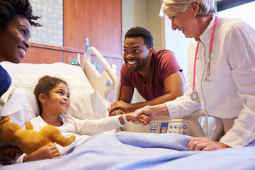 Pediatrician Visiting Parents And Child In Hospital Bed