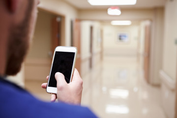 Close Up Of Nurse With Cellphone In Hospital Corridor