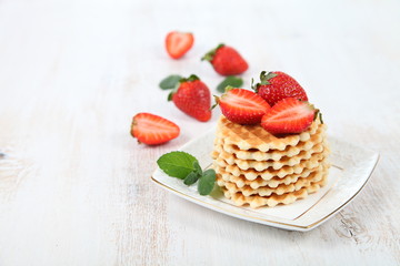 Waffles with strawberries on a wooden table