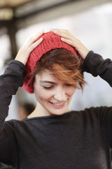 Ritratto di una bella ragazza con cuffietta rossa mentre poggia le mani sulla testa