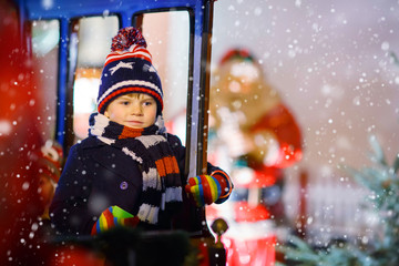 Little kid boy on carousel at Christmas market