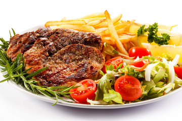 Grilled steak, French fries and vegetables on white background 