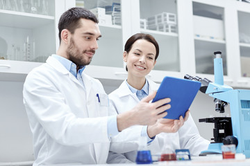 Fototapeta premium scientists with tablet pc and microscope in lab