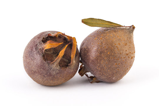 Two fresh organic medlars, isolated on white background
