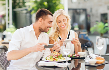 Obraz na płótnie Canvas happy couple with smatphone photographing food