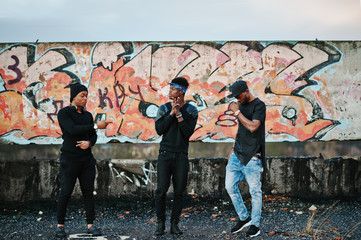 Three rap singers band on the roof background graffiti wall