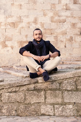 Stylish man sitting on steps and looking at camera