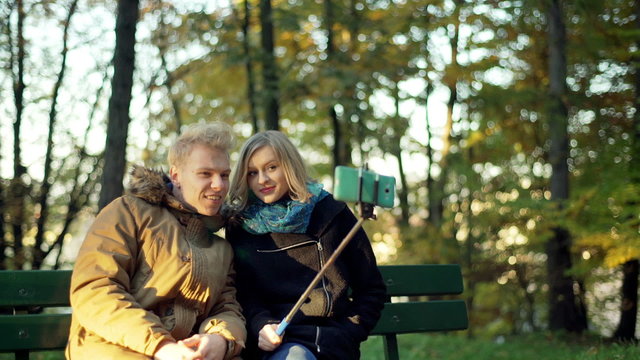 Couple having a selfie stick and doing photos on smartphone in the park
