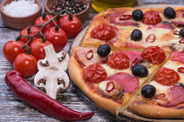 Italian pizza with mozzarella, tomatoes, chilli on wooden background