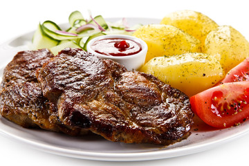 Grilled steaks, boiled potatoes and vegetable salad 
