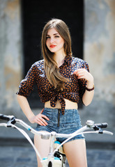 Fototapeta na wymiar Gorgeous girl with long hair is posing on the bicycle