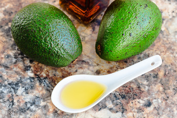 avocado oil in a glass bottle and fresh green avocado