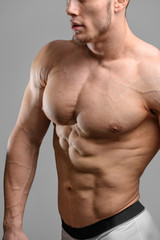 Fototapeta premium Close up shot without face of athletic man over grey background