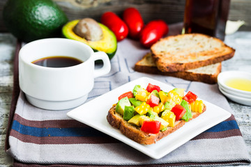 toast with fresh avocado, tomato and corn, a cup of coffee, brea