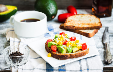 toast with fresh avocado, tomato and corn, a cup of coffee, brea