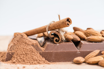 Close-up of still life: white and dark chocolate, almonds, cinna
