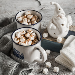 hot chocolate with marshmallows, ceramic Santa Claus, old book and gloves, bright wooden surface, vintage style