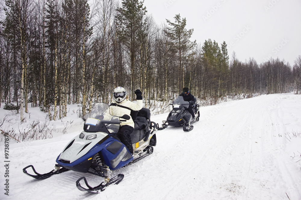 Wall mural Woman and a Man driving snowmobile in Ruka of Lapland