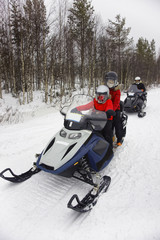 Family driving a snowmobile in Ruka of Lapland, Finland