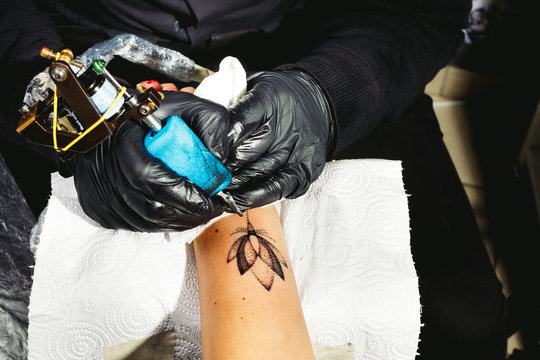 A tattoo artist applying his craft on the young woman's hand