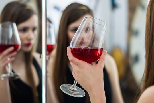Девушка держит в руке бокал с красным вином