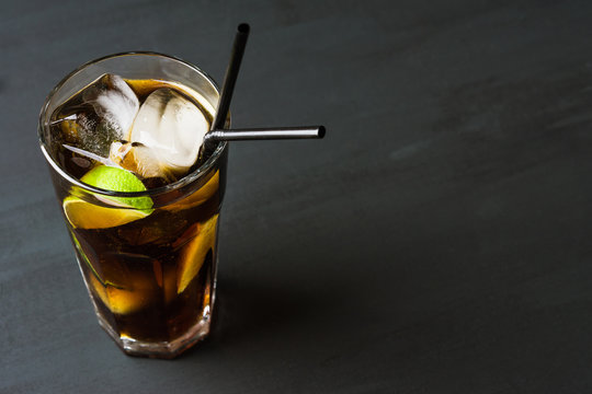 Glass of cola with ice and lime on the rustic background
