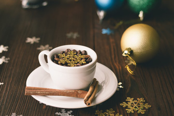 Cup and saucer with a cinnamon stick on a wooden table among Chr