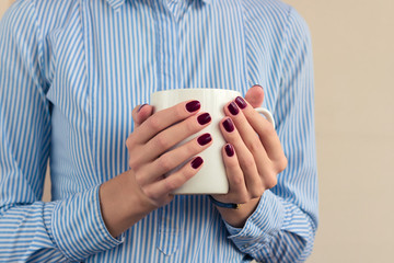 Woman in a blue shirt holding a white cup closeup - Powered by Adobe