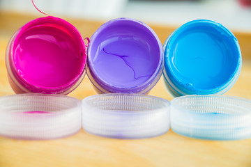 Три баночки с акриловой краской лежат на столе