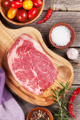 Raw beef steak and spices on wooden table