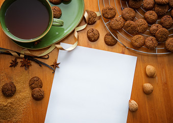 christmas table with ginger cookies, cup of tea and plain paper for wish, top view