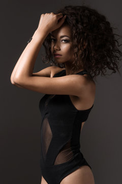 Afro sexy woman posing in black lingerie, looking at camera.