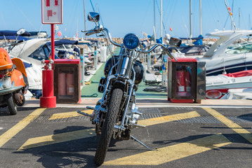 Expensive vintage motorbike in no-parking zone in Spanish marina. Luxury motorcycle parked in Port Adriano on Majorca island in front of yachts - 97402061