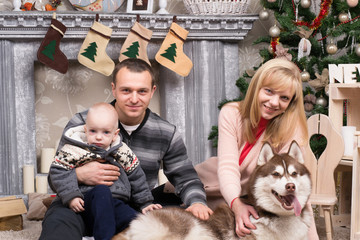 Happy young family  is sitting near  New Year  Christmas tree wi