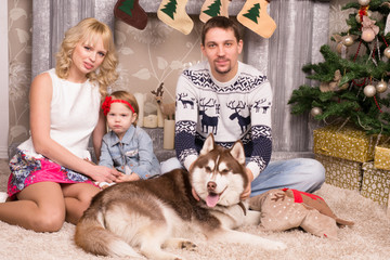 Happy young family  is sitting near  New Year  Christmas tree wi
