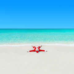 Fototapeta na wymiar Christmas Santa Claus sunbathing on sand at tropical ocean beach
