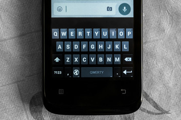 Obraz premium Smartphone. The touch keyboard smartphone on the background of the surface discolored.
