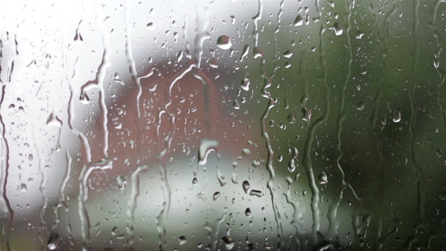 Closeup of raindrops streaming down a glass window pane