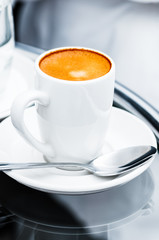 Espresso coffee full cup and saucer by the bed bedside table closeup hotel room service single cup hot drink
