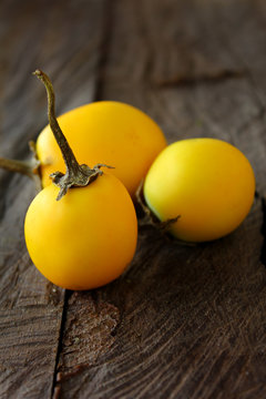 Round small yellow  eggplants on vintage wooden background