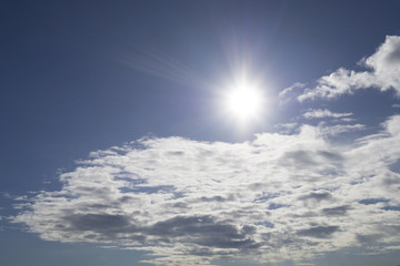 Rays of the sun in the blue sky and white clouds
